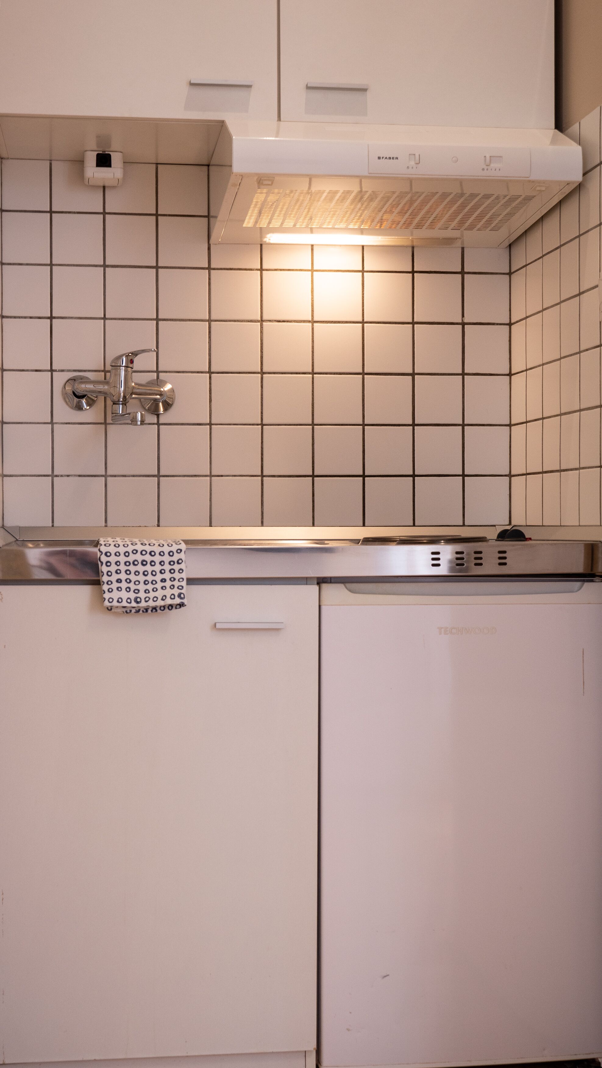 A kitchen with white cabinets, a stainless steel faucet, and a patterned towel on the countertop.