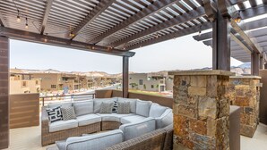 A covered outdoor seating area with a stone wall and a light-colored sofa. - 3BR Sleeps 18 w/ 3 Kings & Bunk Loft - Near Pool (St. George)