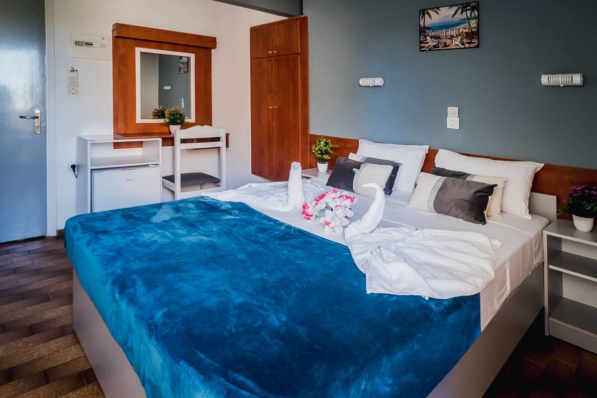 Une chambre bien rangée, avec un lit, un bureau, une armoire et une petite plante en pot.