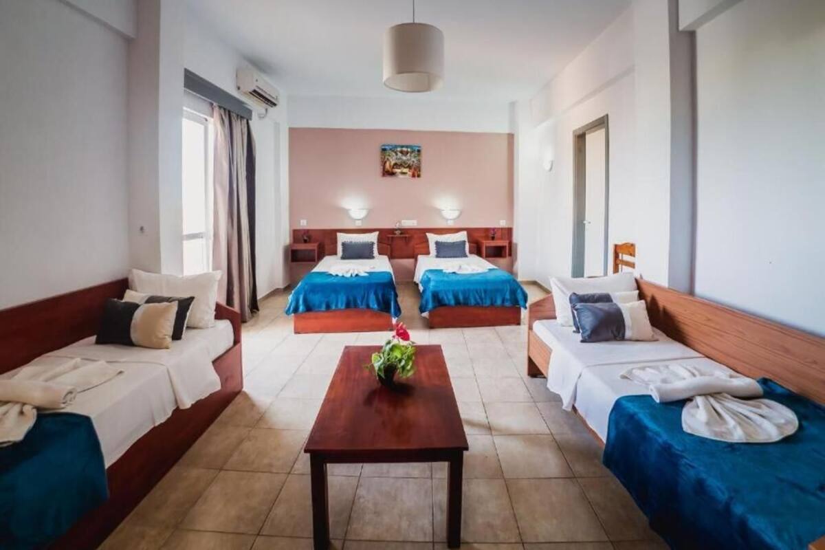 Une chambre d’hôtel avec deux lits simples, un canapé, une table en bois et un tableau au mur.