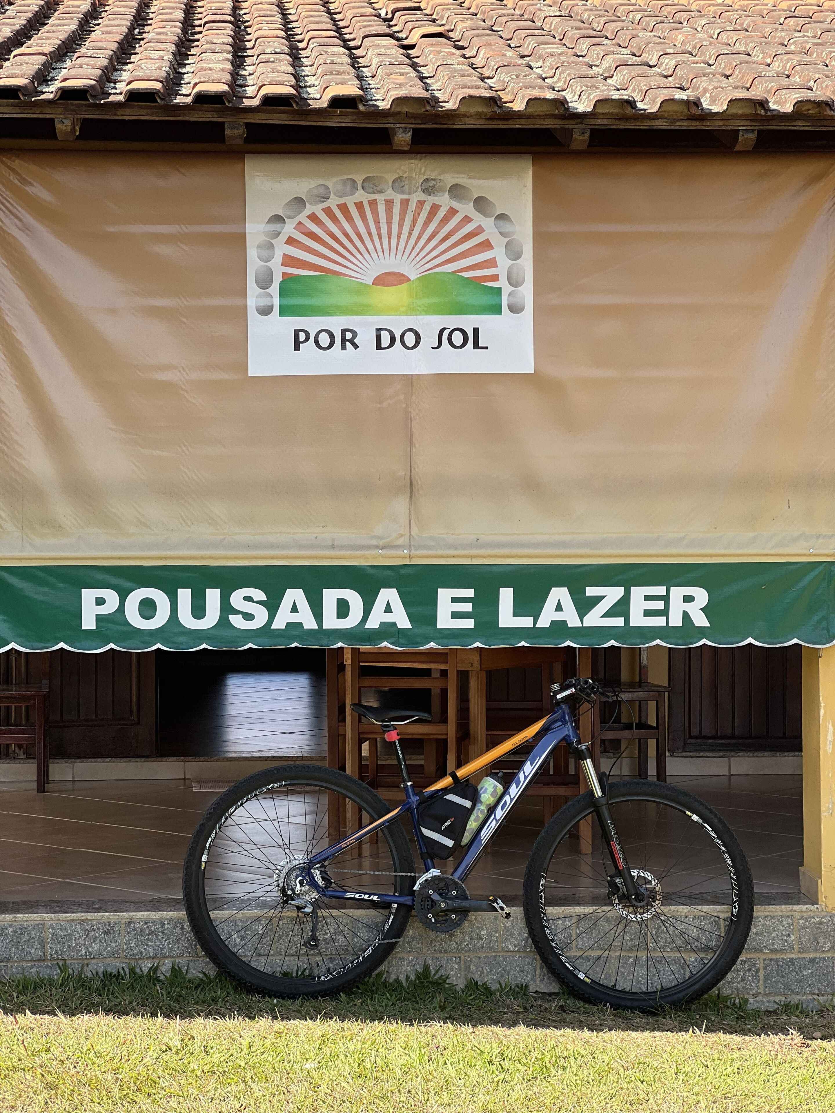 A bicycle parked in front of a building with a sign reading "POUSADA E LAZER".