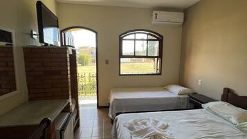 Habitación de hotel con dos camas, televisión, ventilador de techo y ventana.