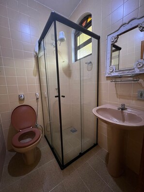 A bathroom with a glass-enclosed shower, a toilet, and a sink.