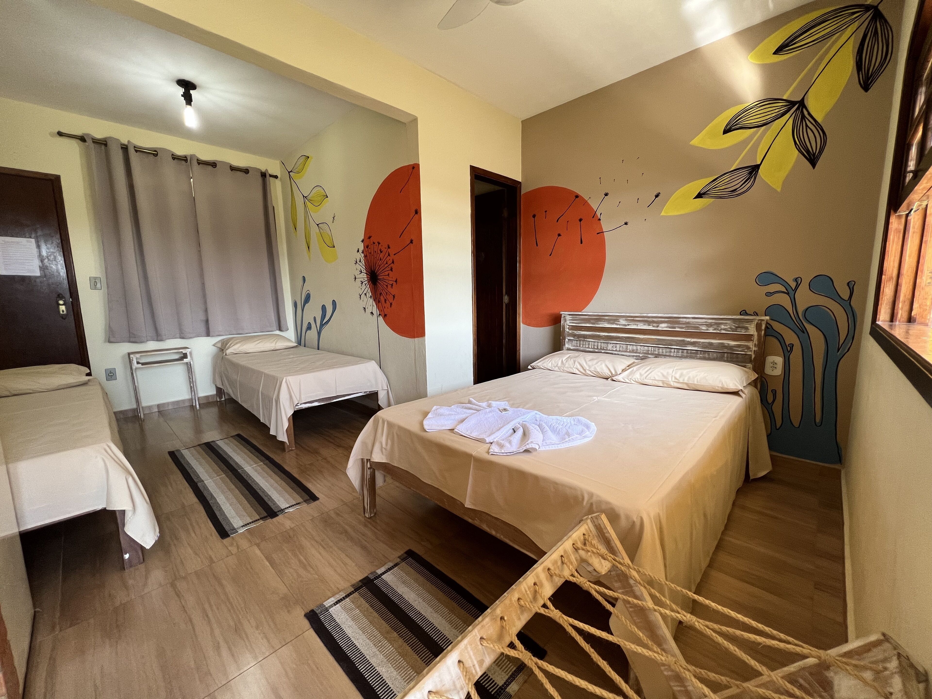 A hotel room with two single beds, a wooden floor, a striped rug, and a wall with abstract art.