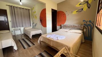 A hotel room with two single beds, a wooden floor, a striped rug, and a wall with abstract art.