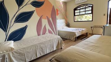 Une chambre d’hôtel avec deux lits, un ventilateur de plafond, un appareil de climatisation et une fenêtre donnant sur un paysage verdoyant.