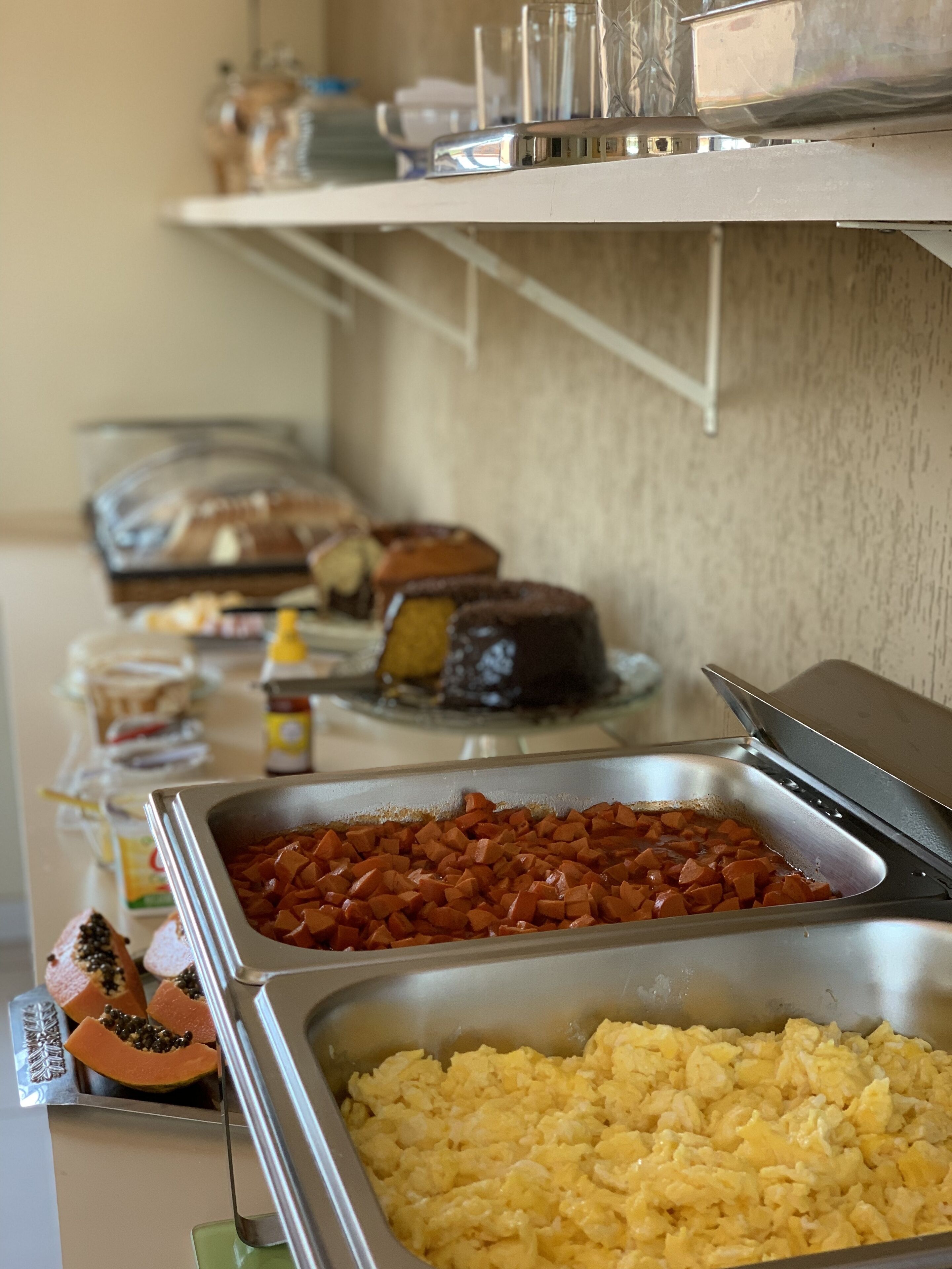 Un bufé con diversos alimentos, incluyendo huevos revueltos, jamón en cubos y pan rebanado.