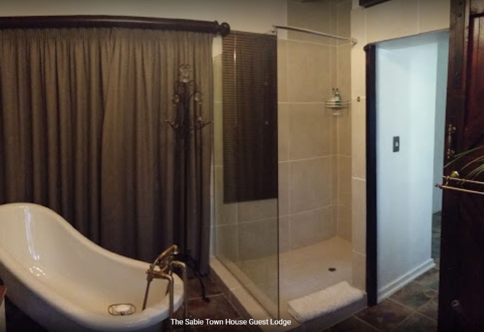 A bathroom with a freestanding bathtub, a glass-enclosed shower, and a door to the right.