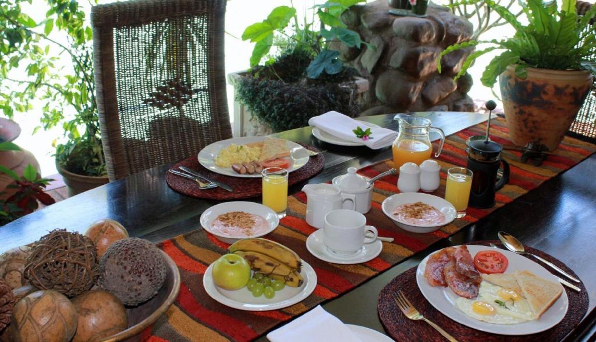 Una mesa de desayuno con diversos platos, entre ellos huevos, tostadas y fruta.