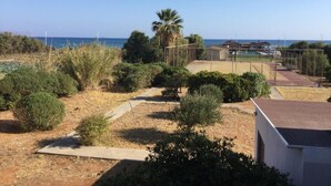A residential area with a sports court, palm trees, and a view of the sea. - Divina Apartments  by Estia (Hersonissos)
