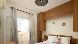A bedroom with a bed, a wooden nightstand, a desk, and a chair. - Divina Apartments  by Estia (Hersonissos)