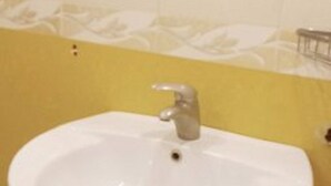 Un baño con un lavabo blanco, paredes amarillas y un espejo sobre el lavabo.
