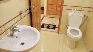Un baño con lavamanos, inodoro y puerta de madera.