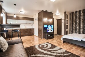 Ein modernes Hotelzimmer mit Sofa, Fernseher, Küchenzeile und einer Wand mit Muster.