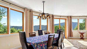 Un comedor con una mesa dispuesta para seis personas, ventanas amplias y vistas al exterior.