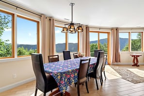 A dining area with a table set for six, large windows, and a view of the outdoors.
