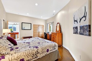 Un dormitorio con cama, escritorio, armario y un cuadro grande en la pared.