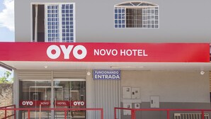 The exterior of OYO Novo Hotel with a clear entrance sign, a glass door, and a red metal gate. - OYO M&J Hotel (Santo Antônio do Descoberto)