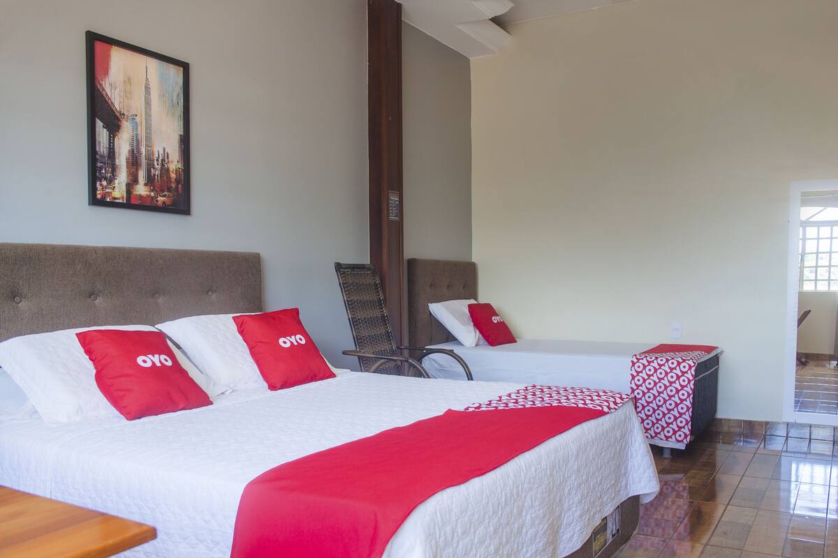 A hotel room with two beds, each with red and white bedding, and a large painting on the wall.