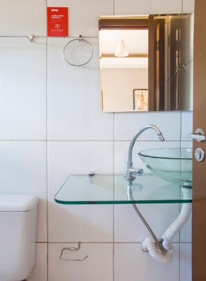 A modern bathroom with a glass sink, a toilet, and a towel rack. - OYO M&J Hotel (Santo Antônio do Descoberto)