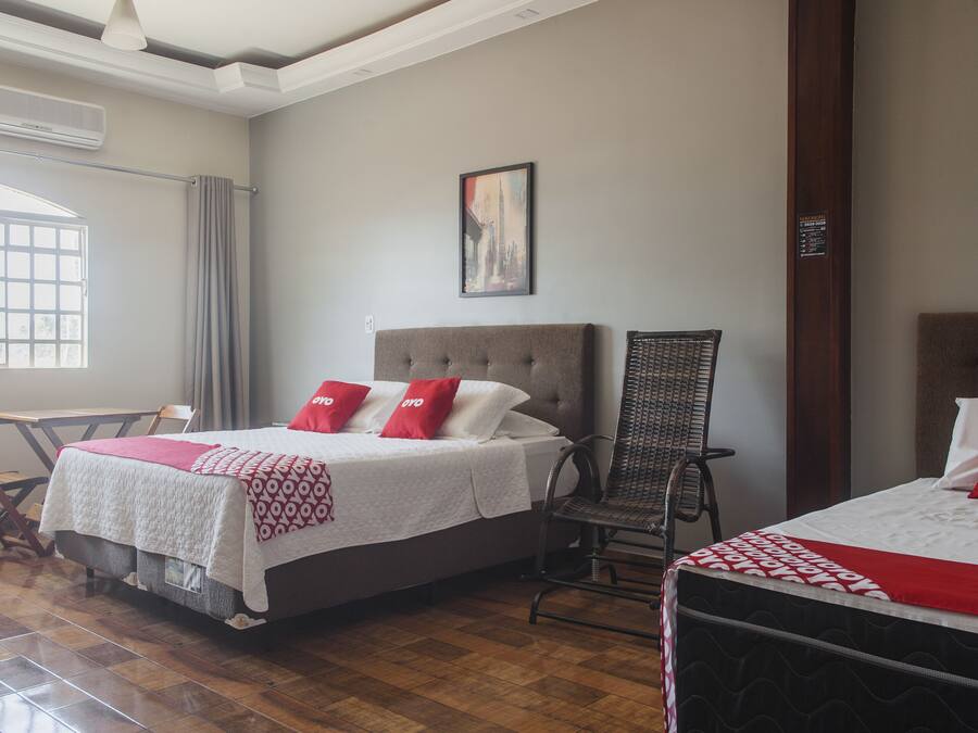 A hotel room with a bed, a chair, a table, and a window.