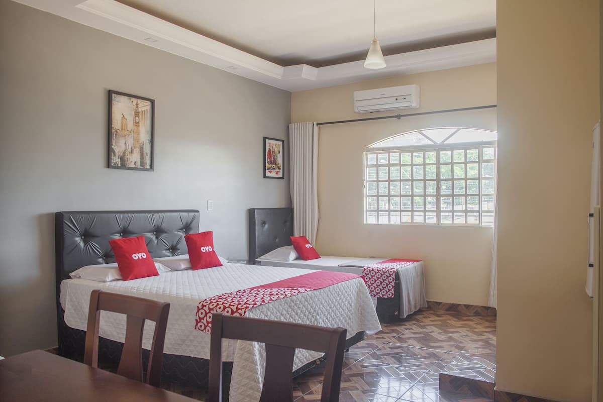 A hotel room with two beds, a dining table, and a window with a view.