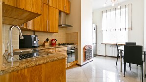 A modern kitchen with wooden cabinets, stainless steel appliances, a granite countertop, and a dining area with a table and chairs. - MinskLux Apartment 2 bedroom Nezavisimosti 12 (Minsk)