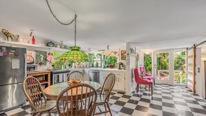 A kitchen with a checkered floor, wooden chairs, a round table, and a green hanging light fixture.