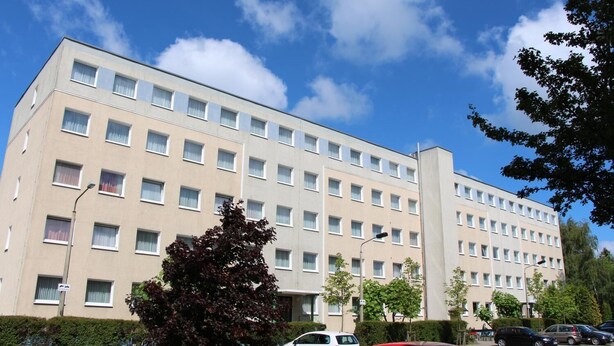 A multi-story hotel with a uniform facade, numerous windows, and a parking area with several cars. - Schlafhaus Dünenweg 16 (Heringsdorf)