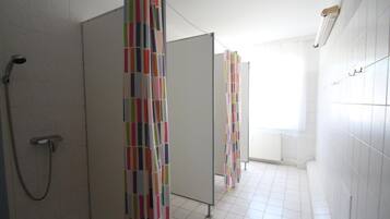 Ein Badezimmer mit weiß gefliesten Wänden, einem Duschbereich und bunten, gestreiften Vorhängen.