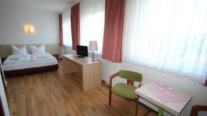 A hotel room with a bed, desk, chair, and a table with a lamp. - Schlafhaus Dünenweg 16 (Heringsdorf)