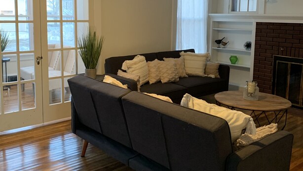 Ein Wohnzimmer mit einem dunklen Sofa, einem runden Couchtisch und einem Deckenventilator.
