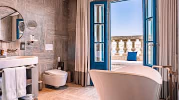 Ein modernes Badezimmer mit Badewanne, Toilette und Waschbecken. Über dem Waschbecken hängt ein großer Spiegel und es gibt ein Fenster mit Vorhängen.