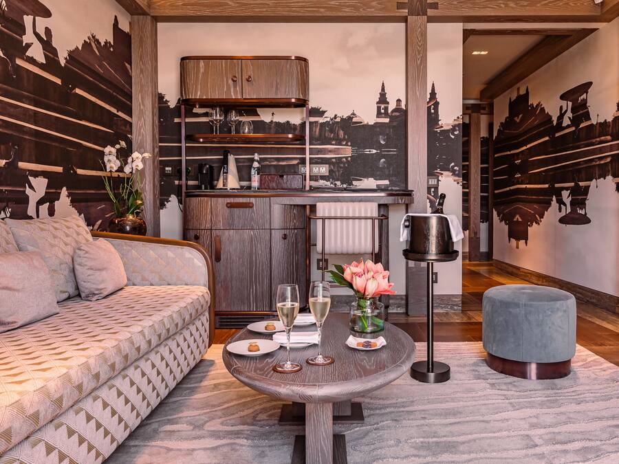 Un salon moderne avec un canapé, une table ronde ornée d’un vase de fleurs, et un coin cuisine à l’arrière-plan.