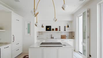 A modern kitchen with white cabinetry, a marble countertop, and a central island.