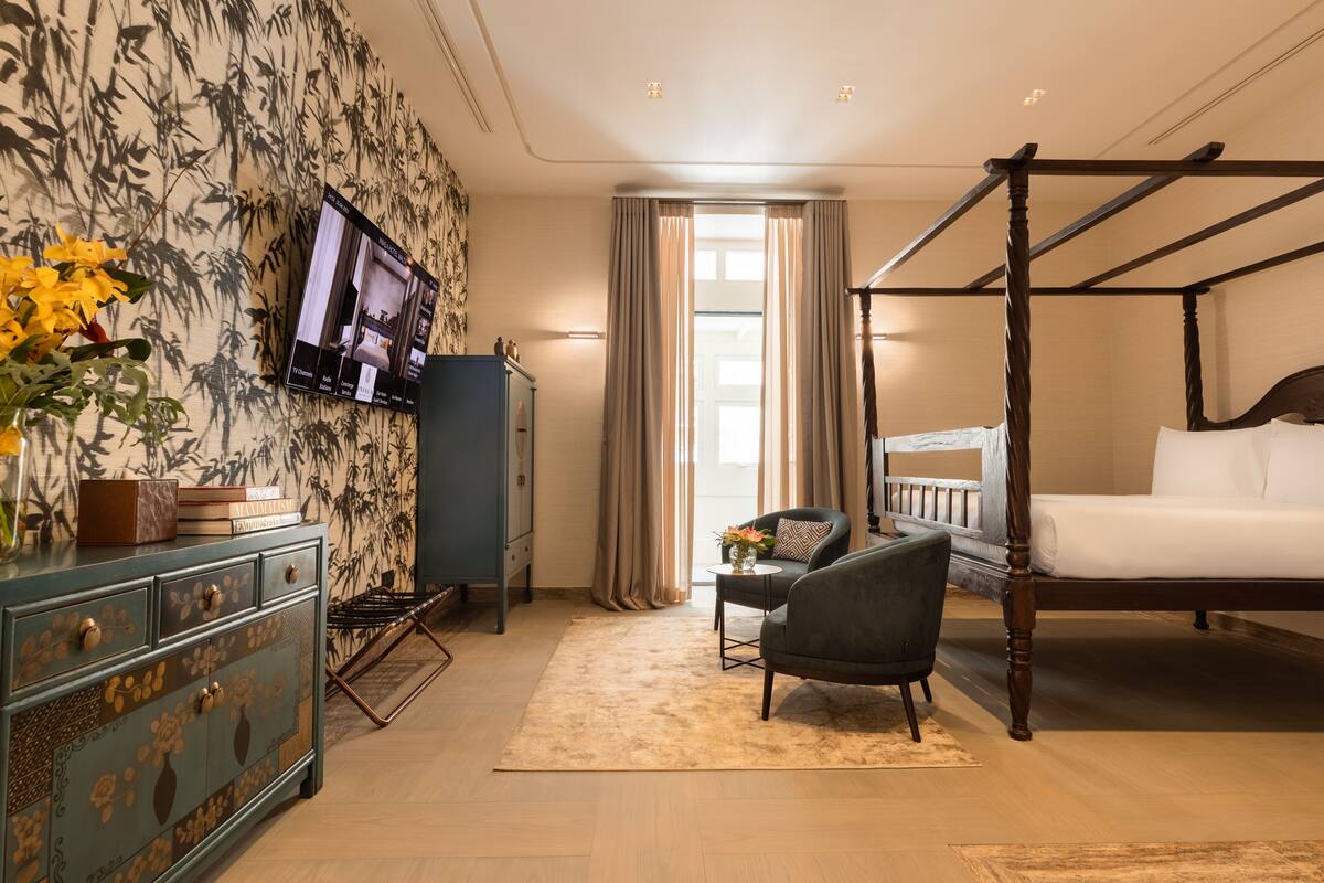 Un dormitorio con cama con dosel, televisor montado en la pared, escritorio con silla y armario.