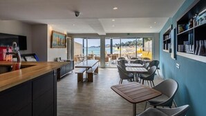 A modern restaurant with a bar area, seating, and a view of the beach. - Roc Hotel (Le Lavandou)