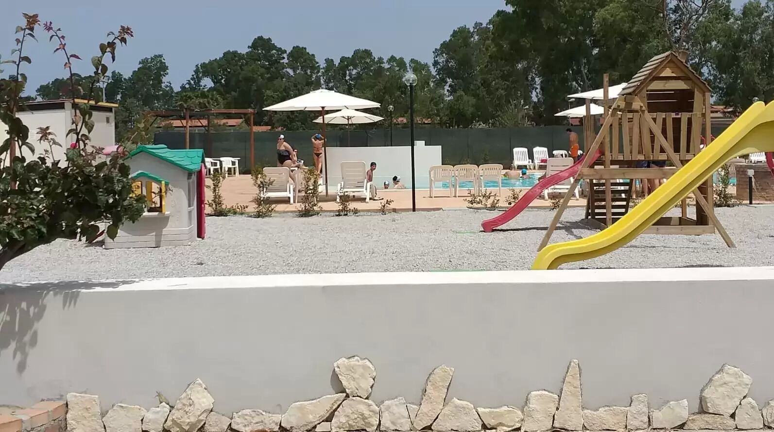 A children's play area with a pool, slides, and a wooden playhouse.