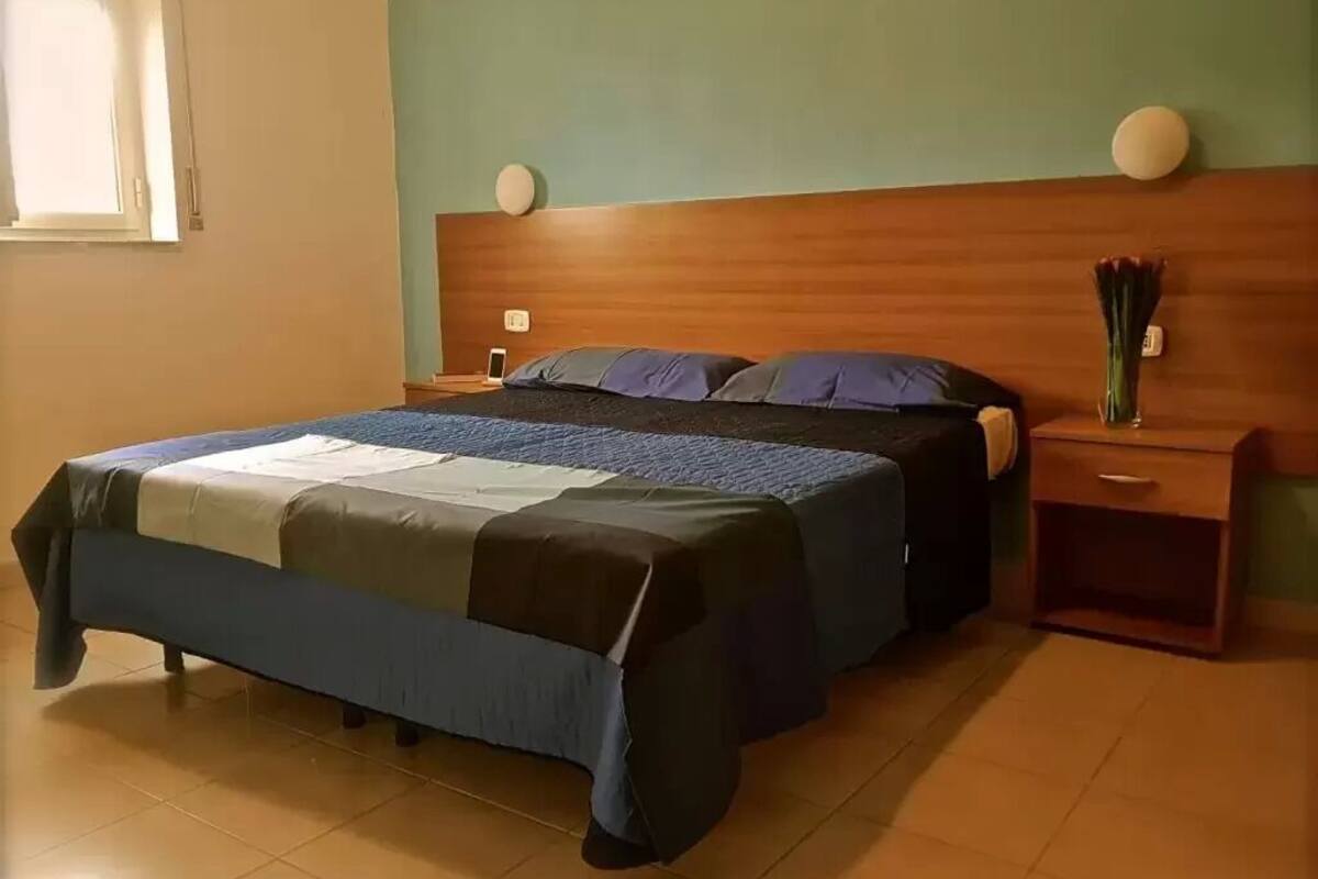 A bedroom with a bed, nightstands, and a wall-mounted clock.