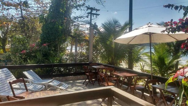 Um pátio externo com cadeiras de estar, mesas e um guarda-sol.