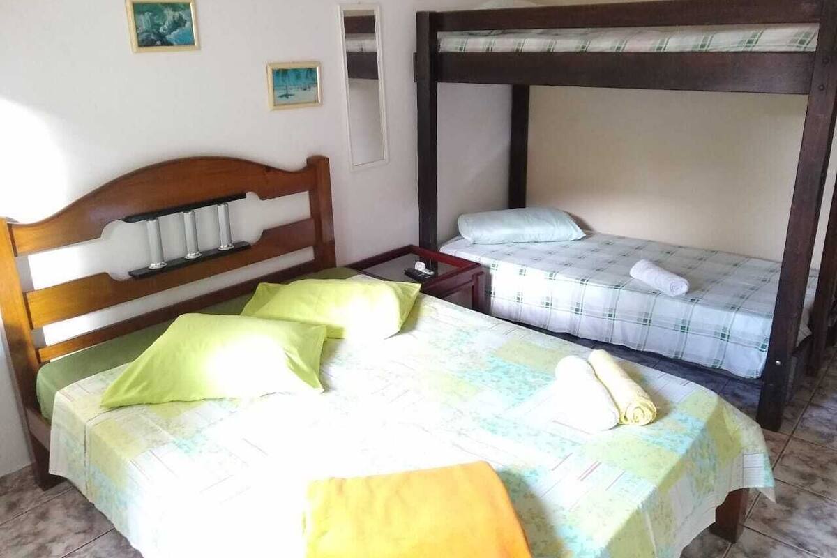 Une chambre avec deux lits, dont l’un est doté d’une tête de lit en bois et l’autre d’un cadre en métal. On trouve des oreillers et une serviette roulée sur les lits.