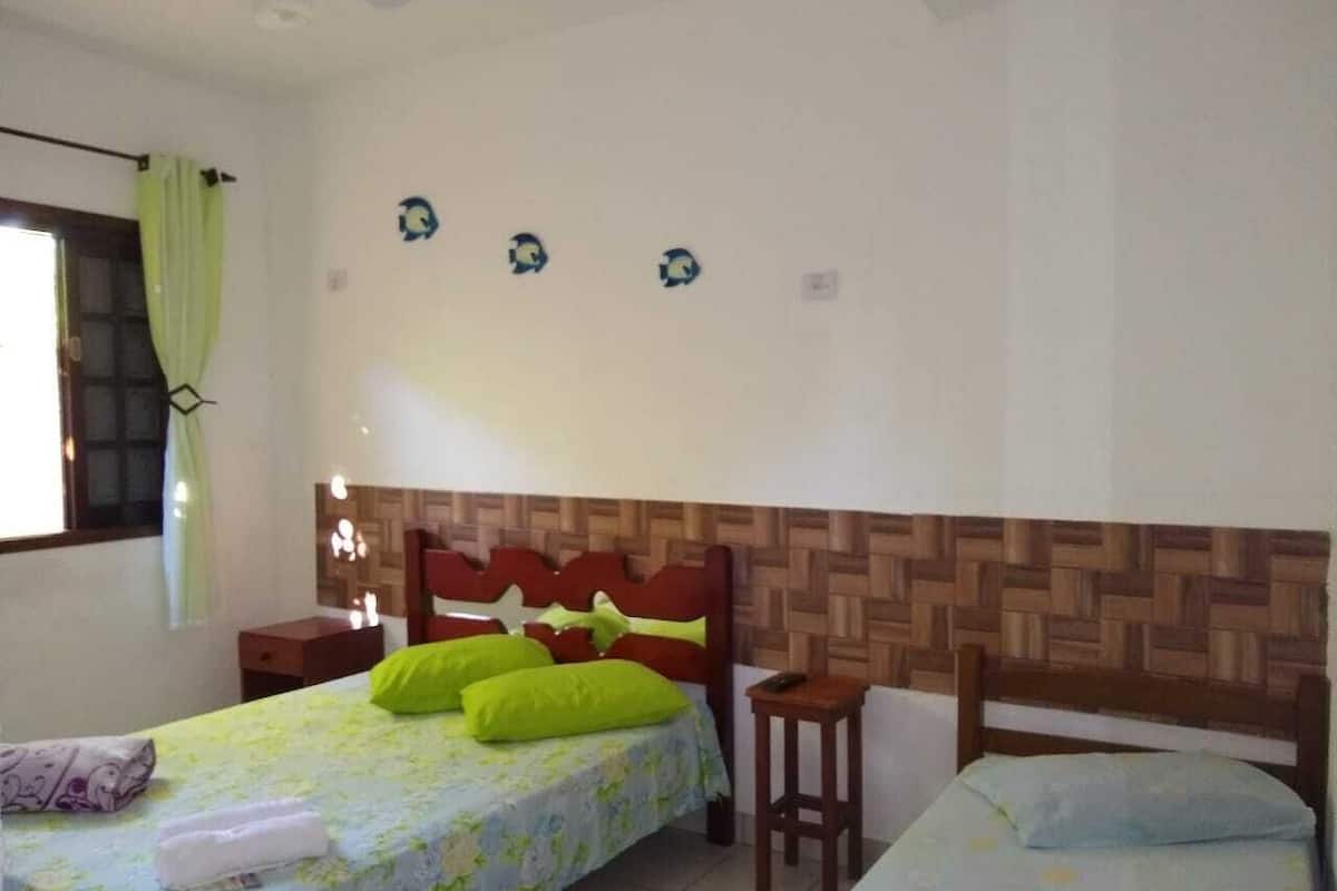 Une chambre à coucher avec un lit, une table de chevet, une petite table et une fenêtre avec des rideaux.