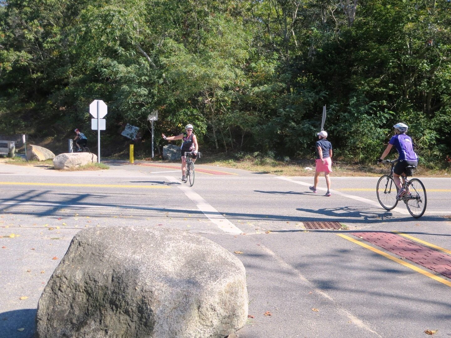 Une route avec des cyclistes et un gros rocher au premier plan.