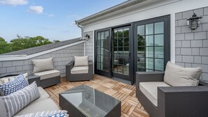 Een terras op het dak met rieten meubels, een glazen tafel en een schuifpui.