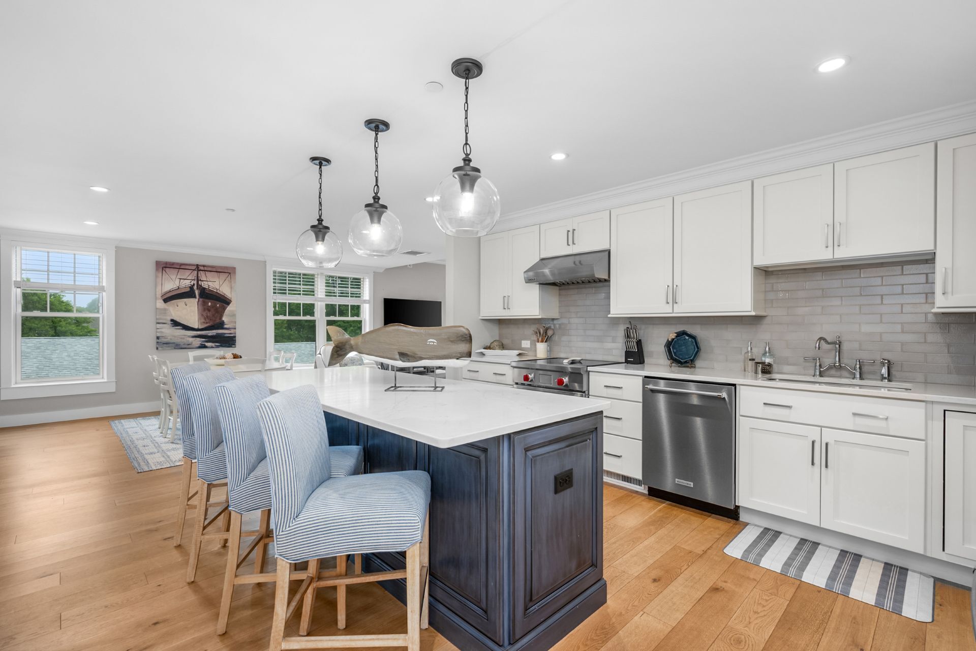 A modern kitchen with white cabinetry, a central island, and pendant lighting.
