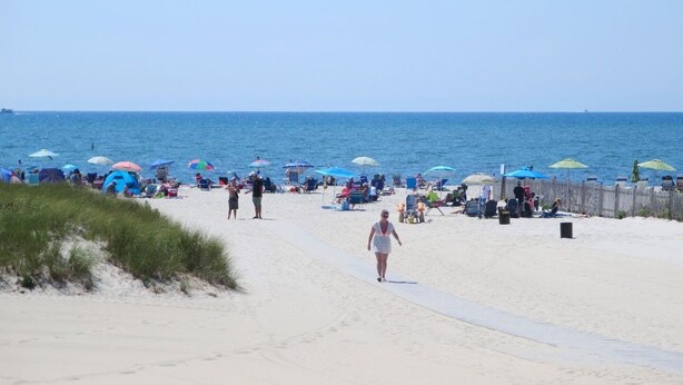 Een strand met mensen, parasols en ligstoelen.
