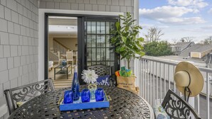 Un balcon avec une table dressée pour deux personnes, un pot de fleurs et un sac muni d’une étiquette.