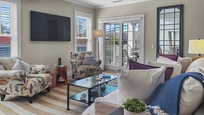 Un salon moderne comprenant un canapé, des fauteuils, une table basse et un téléviseur.