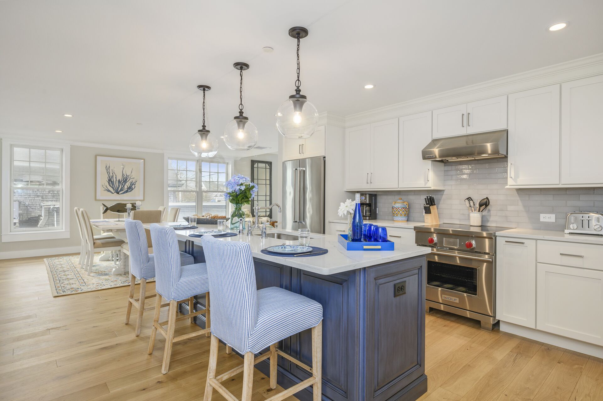 A modern kitchen with white cabinetry, stainless steel appliances, and a central island with bar stools.
