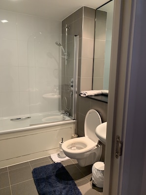 A modern bathroom with a glass-enclosed shower, a white toilet, and a bathtub. - Remarkable 2-bed Apartment (Leeds)
